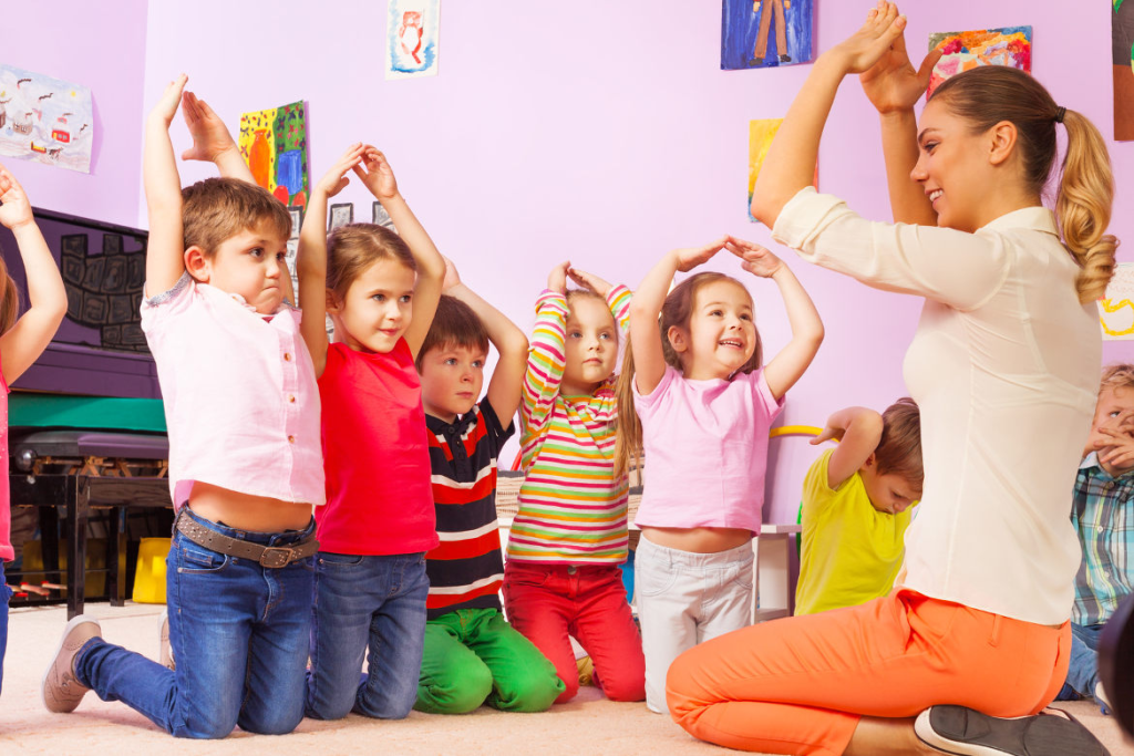 Nursery staff interacting with children in a UK childcare setting.